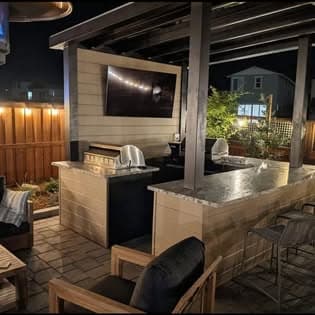 Outdoor kitchen and bar under a pergola with string lights at night
