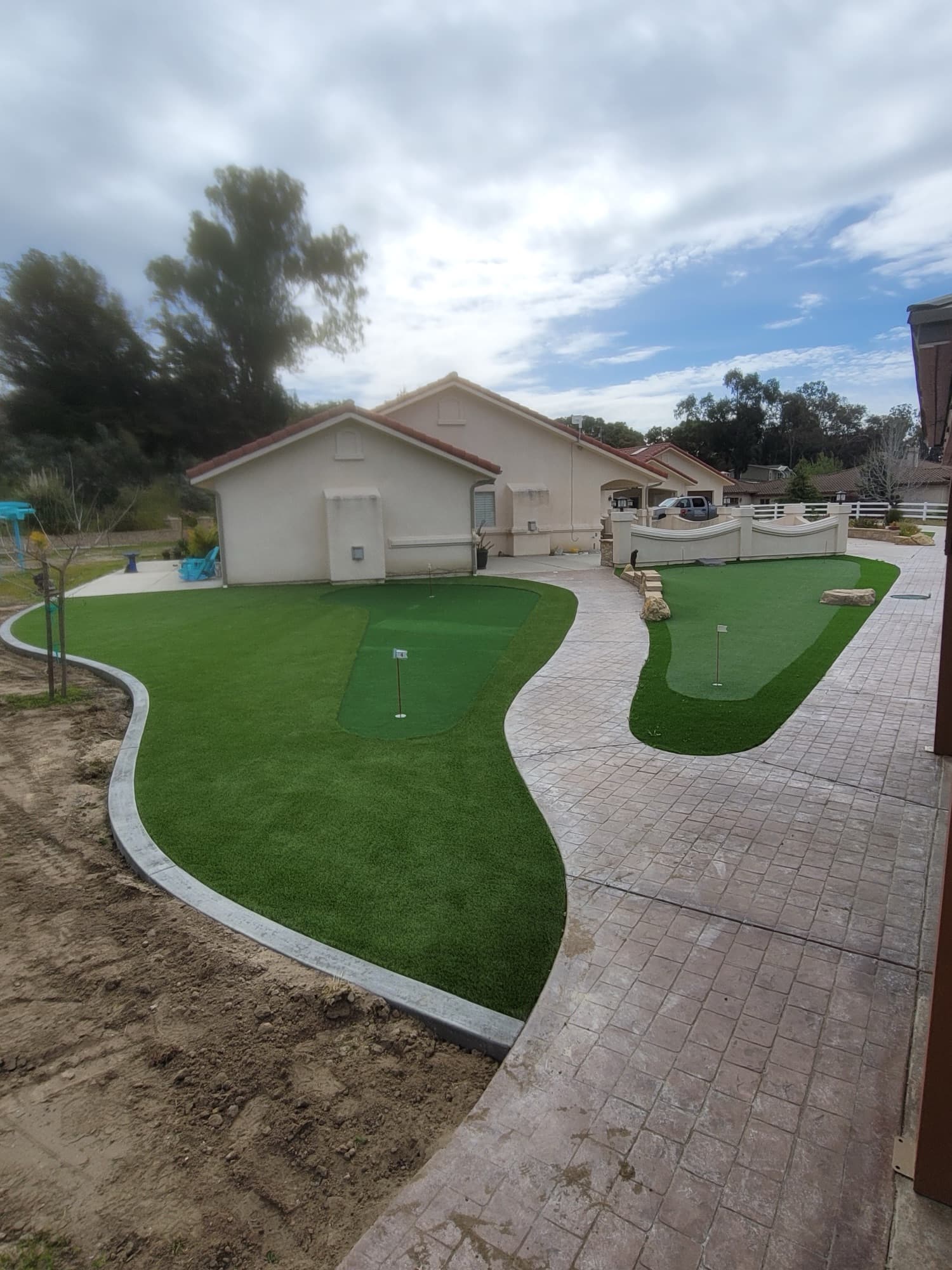Large-lot backyard with putting green, stamped concrete, and new turf