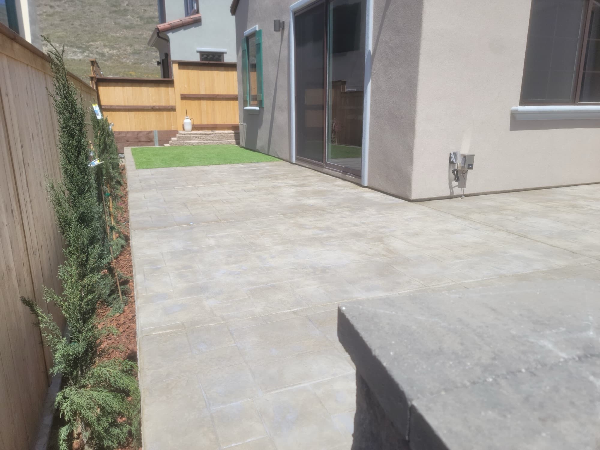 New paver patio and young privacy trees on a new-build home