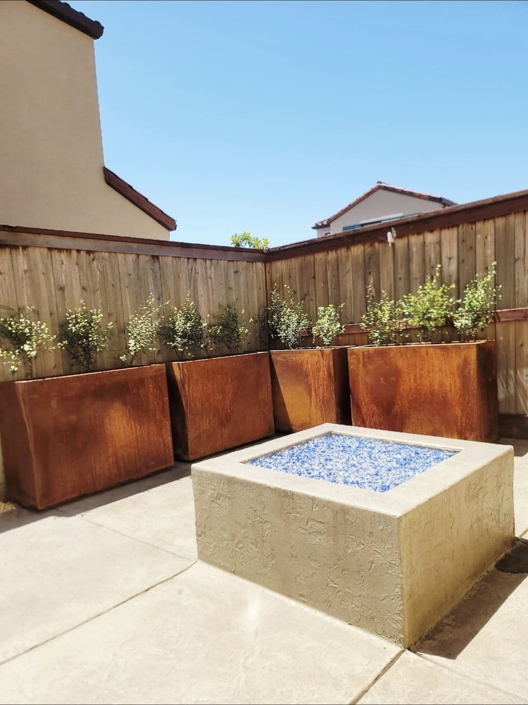 Square fire pit with blue fire glass and corten steel planters