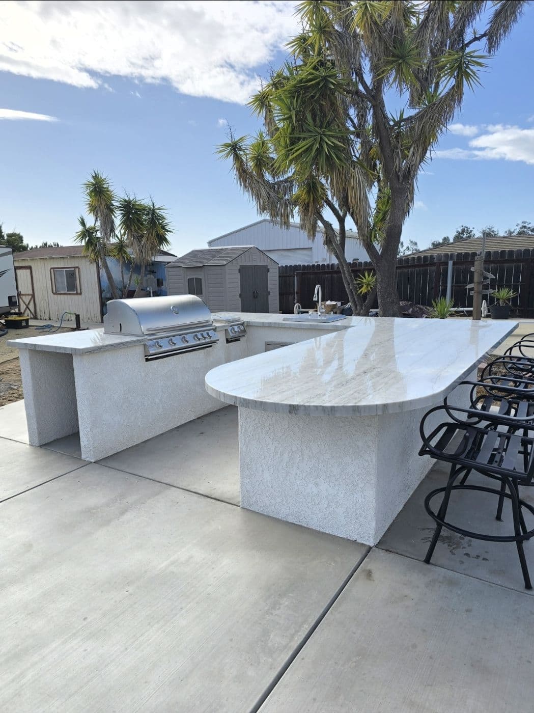 Outdoor kitchen island with bar seating on a concrete patio
