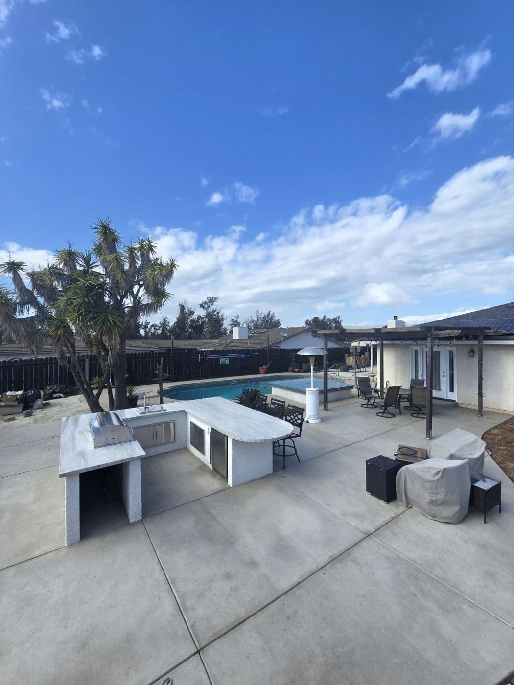 Outdoor kitchen island and pool on a poured concrete patio