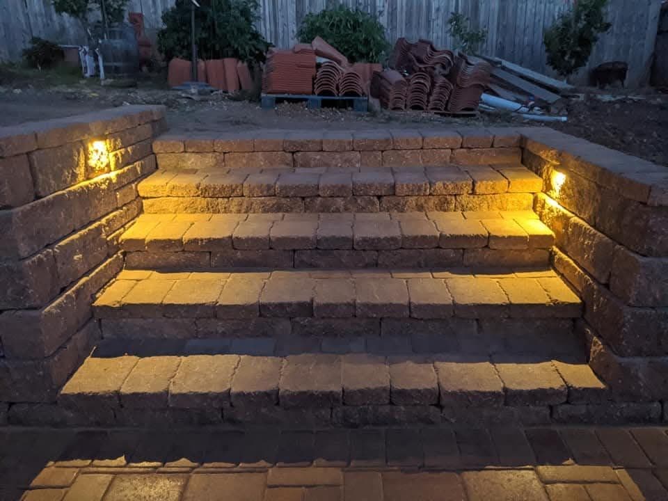 Paver steps and retaining wall with built-in lighting at dusk