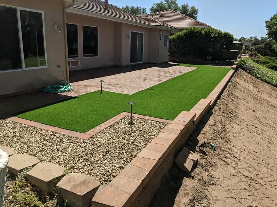 Backyard putting green bordered by a block retaining wall
